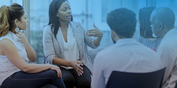 Group of five people sat on chairs in a circle and engaged in discussion. 